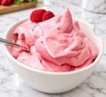 Strawberry Cheesecake Protein Fluff served in a white bowl with fresh raspberries on top.